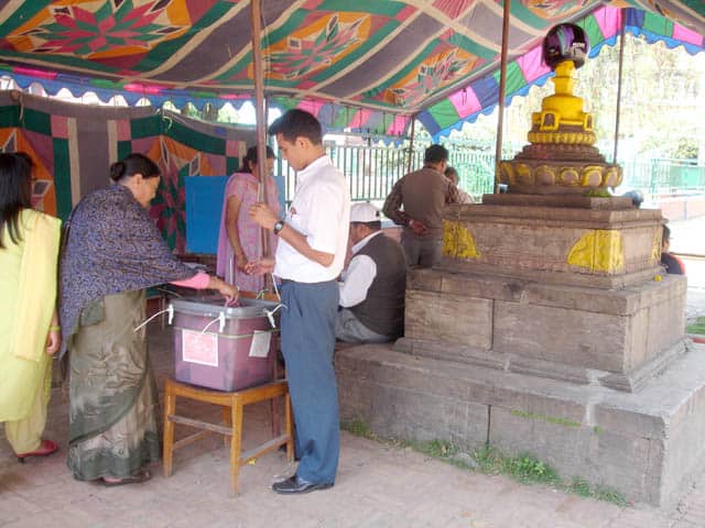 A woman collects her first ballot as an election officer explains how to vote.
