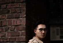 Filmmaker Vincent Huang Builds Connection Through Visual Storytelling person posing in front of brick wall